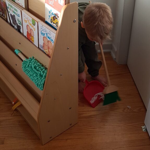 toddler practicing independence sweeping floor Montessori